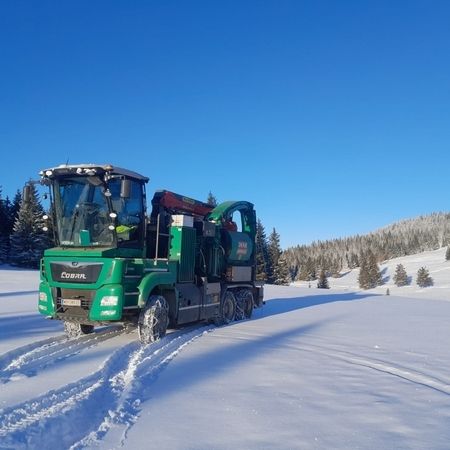 Ein grüner Lastwagen fährt über ein schneebedecktes Feld.