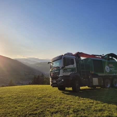 Ein großer Lastwagen steht auf einer grasbewachsenen Anhöhe und bietet einen malerischen Anblick in der Natur.