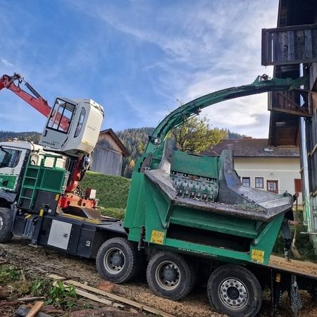 Ein Lkw lädt Holz in ein Gebäude, während Arbeiter die Materialien sorgfältig organisieren.