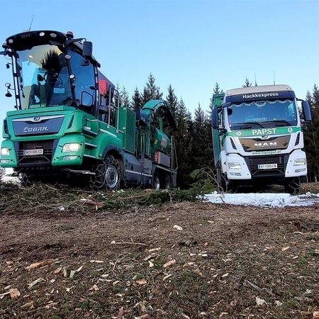 Zwei Lastwagen stehen auf einem Hügel geparkt, umgeben von einer malerischen Landschaft.