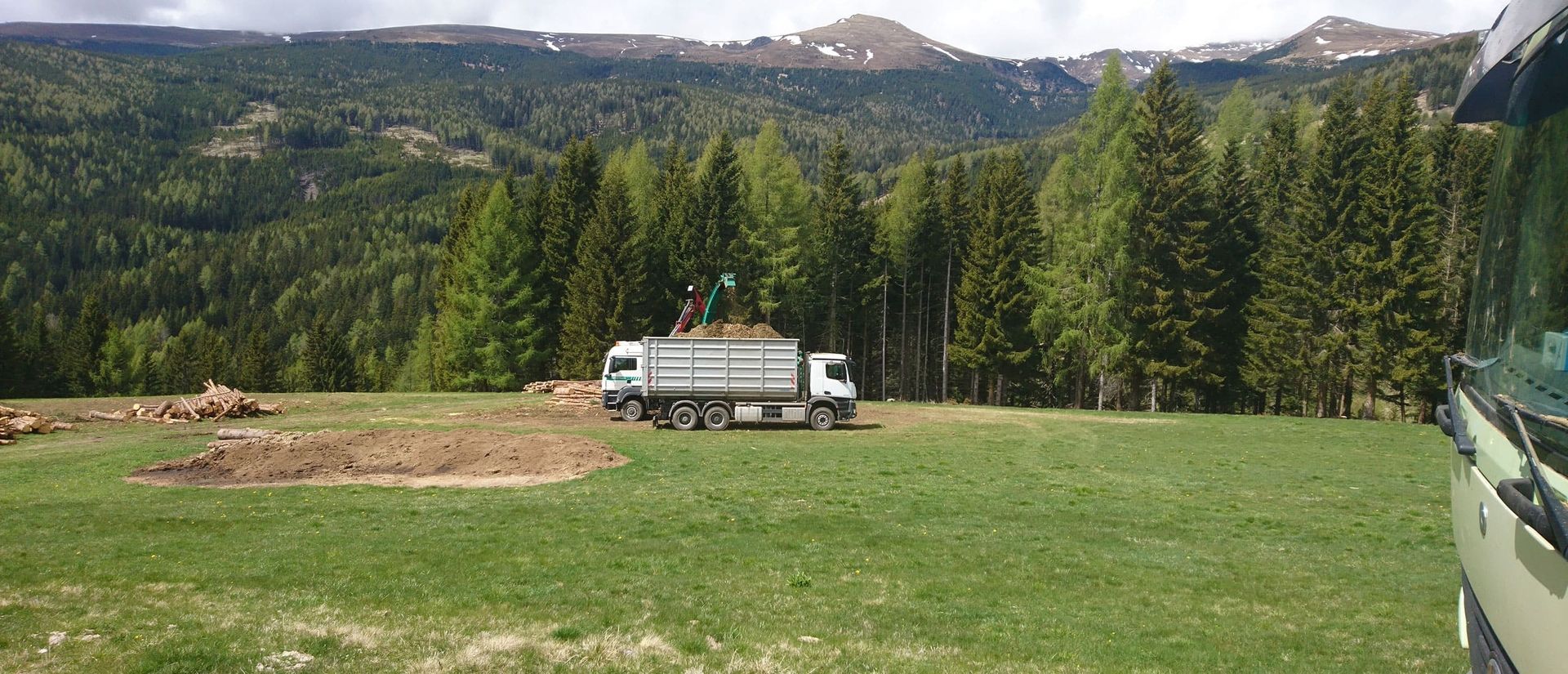 Zwei weiße LKW mit Hackgut stehen mitten in einer Grünfläche.